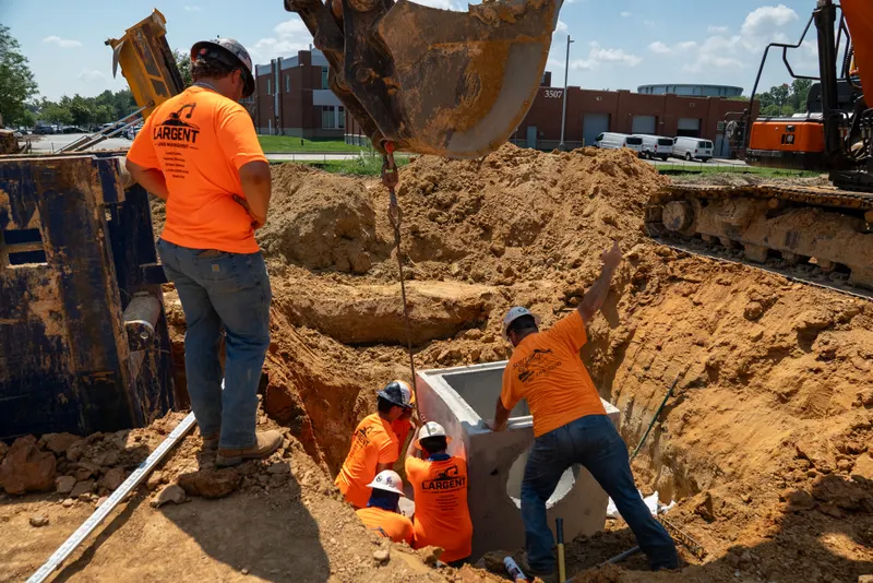 Crew setting a precast structure in a shored trench