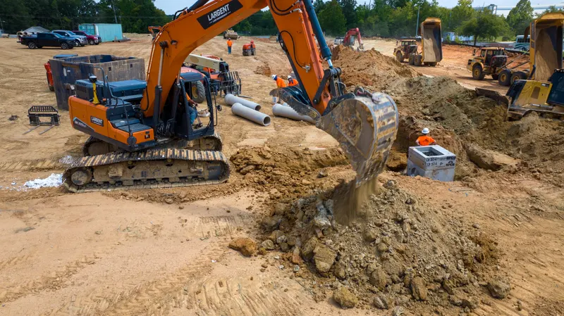 Excavator dumping spoil beside the trench, seen from above