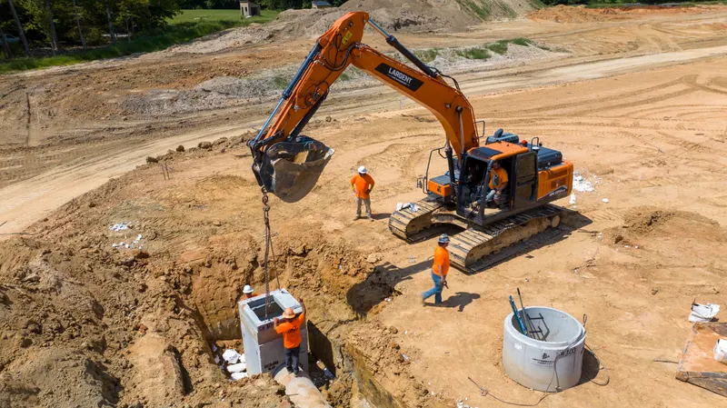 Excavator setting a storm structure with the crew in the trench