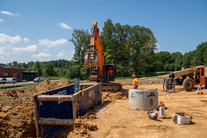 Excavator working beside a trench box on a Largent site