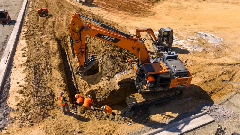 Aerial view of an excavator trenching beside new curb